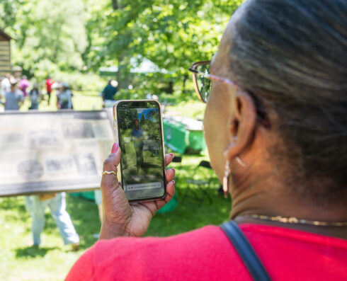 A woman holds her phone and views an interactive video.