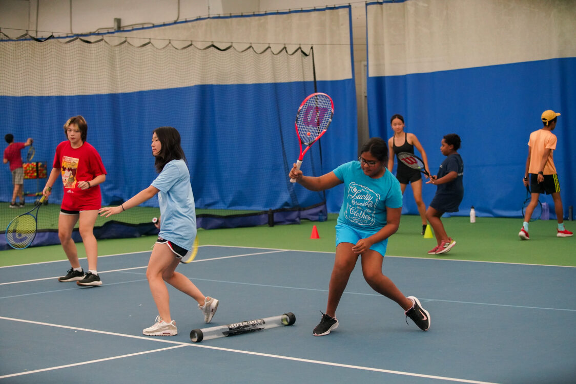 camper learning to return the ball at indoor tennis camp